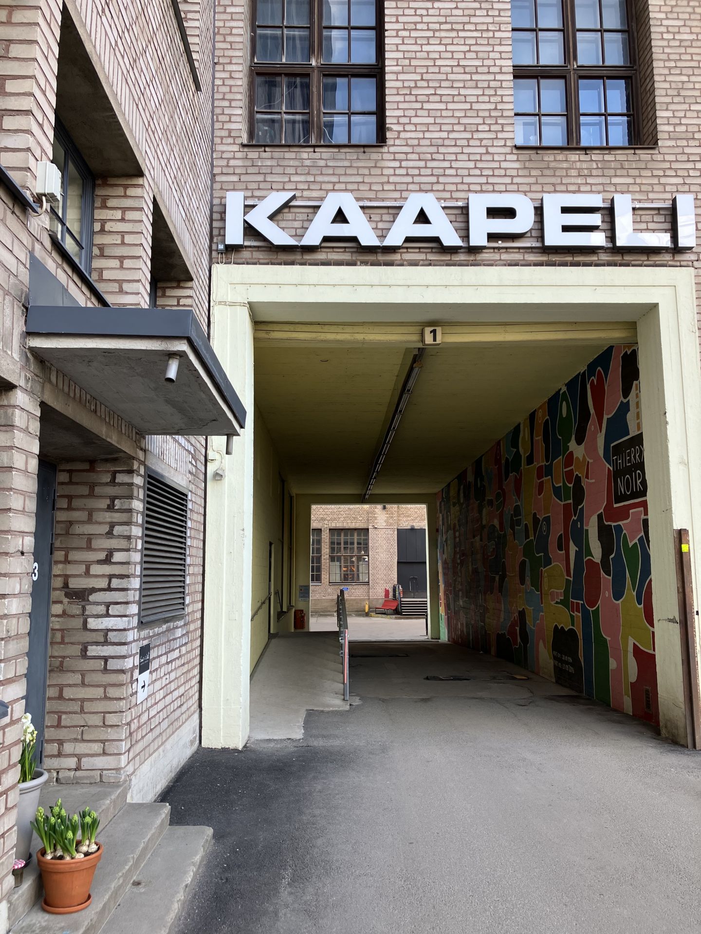 En bild på en portgång vid ett tegelhuset. Ovanför portgången står det Kaapeli.