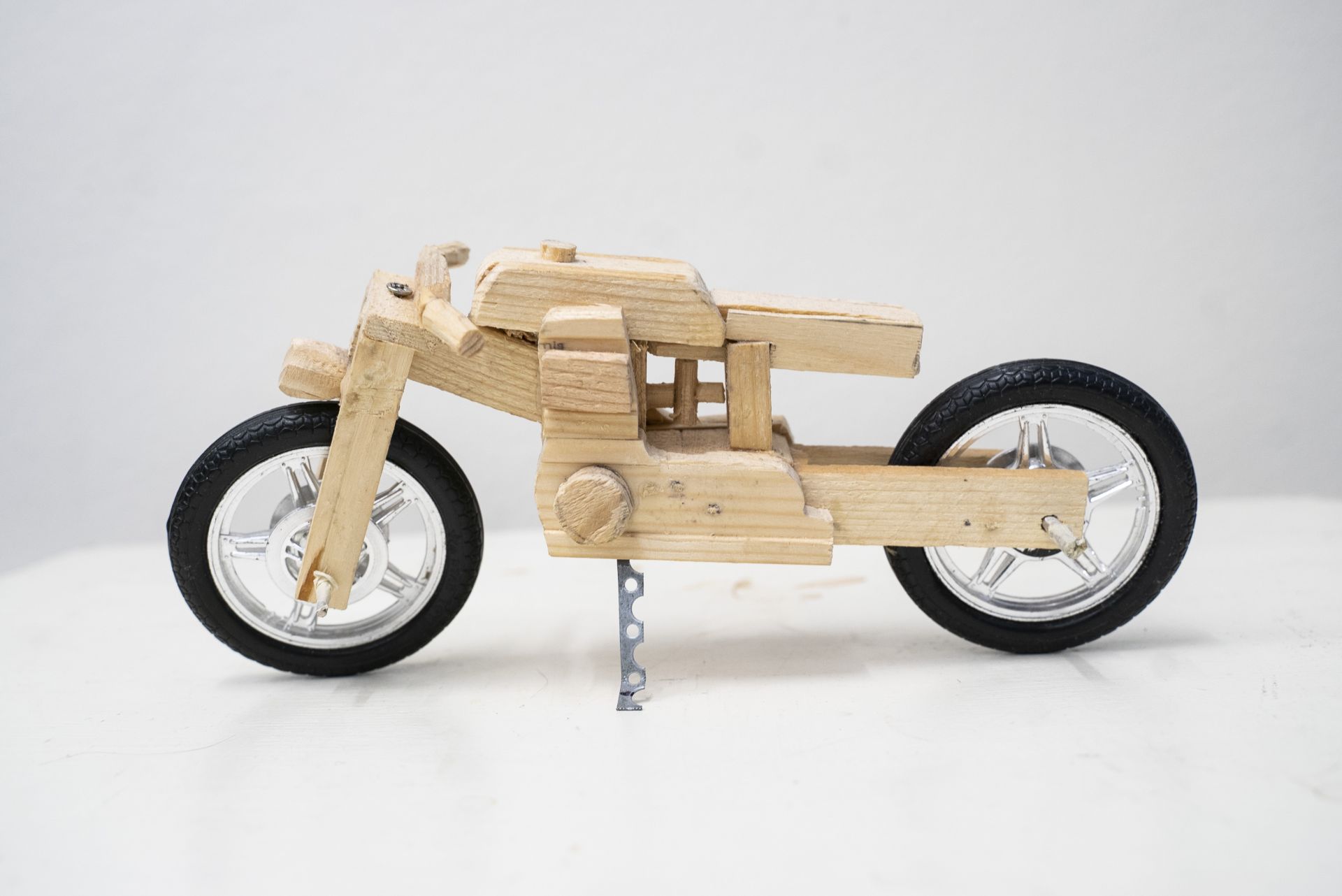 Pienoismalli Harley Davidson-moottoripyörästä. Pienoismalli on tehty puusta ja metallisista osista kuten pyöristä.